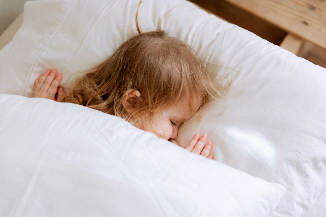 Bambina che dorme su seta bianca